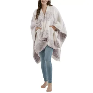 A person is wearing a cozy, sherpa-textured poncho-style wrap with a checkered pattern in soft colors over skinny blue jeans.