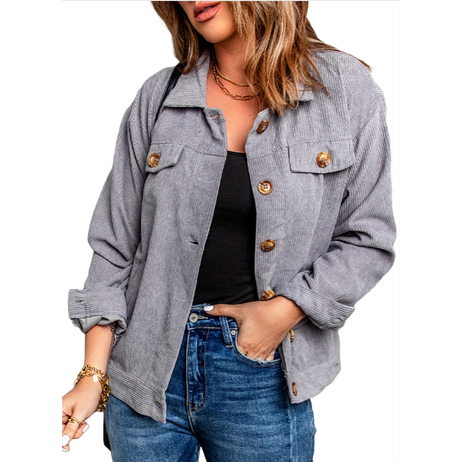Gray corduroy shacket featuring a button-up front, chest pockets with button closures, long sleeves, and a relaxed fit. Worn over a black top and paired with blue jeans.