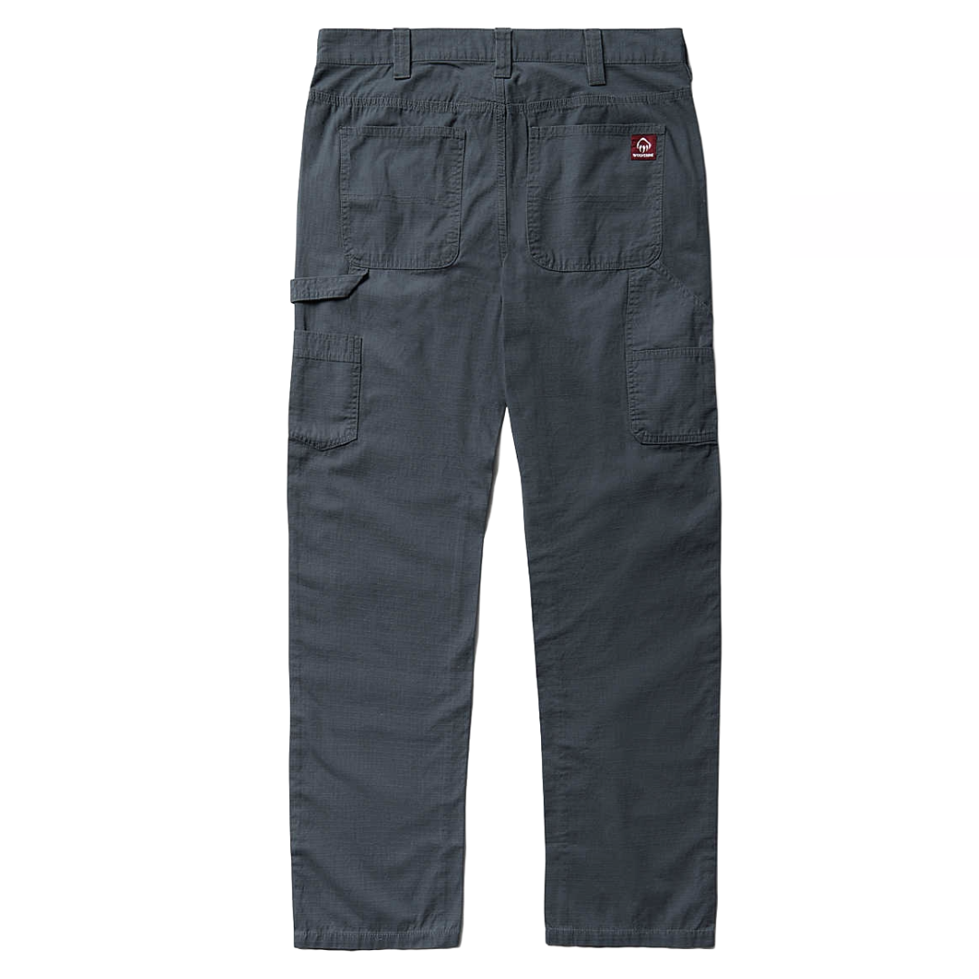 Wolverine Carpenter Pants in gray feature a loose fit with large belt loops, two back pockets, and side cargo pockets for utility. They have reinforced stitching and a durable, textured fabric suitable for work environments.