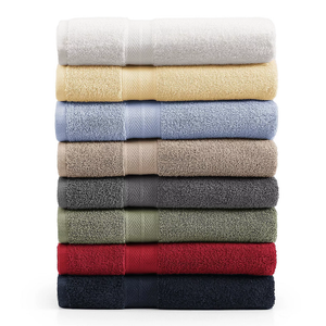 A stack of eight neatly folded bath towels in various colors: white, yellow, light blue, beige, gray, olive green, red, and navy blue.