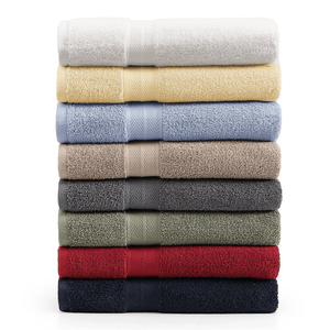 A stack of eight neatly folded bath towels in various colors: white, yellow, light blue, beige, gray, olive green, red, and navy blue.
