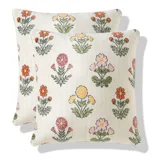 Two square pillows feature a pattern of colorful embroidered flowers, including yellow, pink, and orange blooms on a light background.
