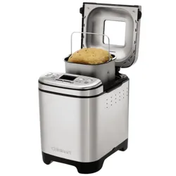 A stainless steel bread maker with a digital display, open lid, and a bread loaf inside the baking pan.