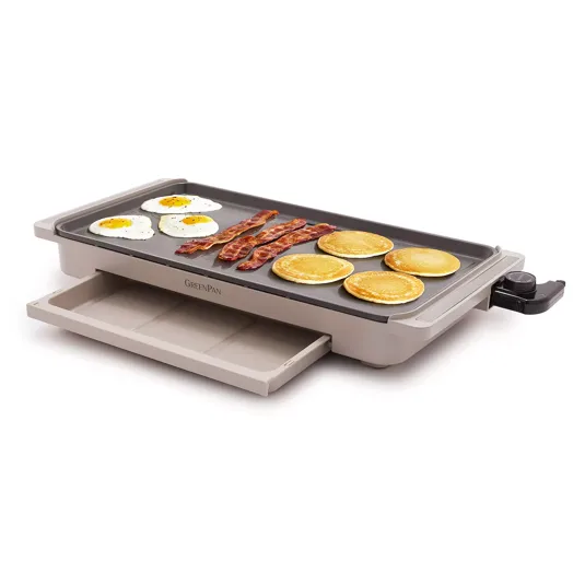 An electric griddle with a non-stick surface is cooking eggs, bacon, and pancakes, with an adjustable temperature dial and a slide-out drip tray.