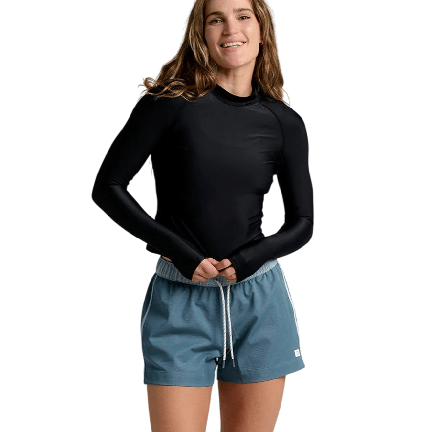 A person is wearing a long-sleeve black rash guard and light blue drawstring shorts with white stripes on the sides.
