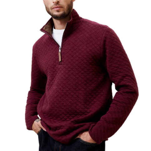 A men's quilted half-zip pullover sweater in deep red, featuring a textured diamond pattern with a collar and leather pull tab, worn over a white shirt with dark jeans.
