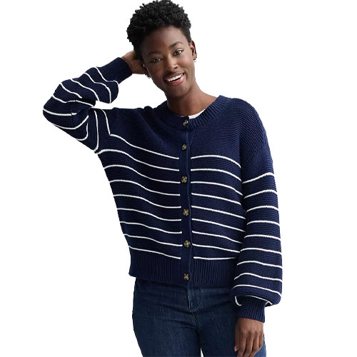 A person wearing a navy blue cardigan with white horizontal stripes and gold buttons, paired with dark jeans.