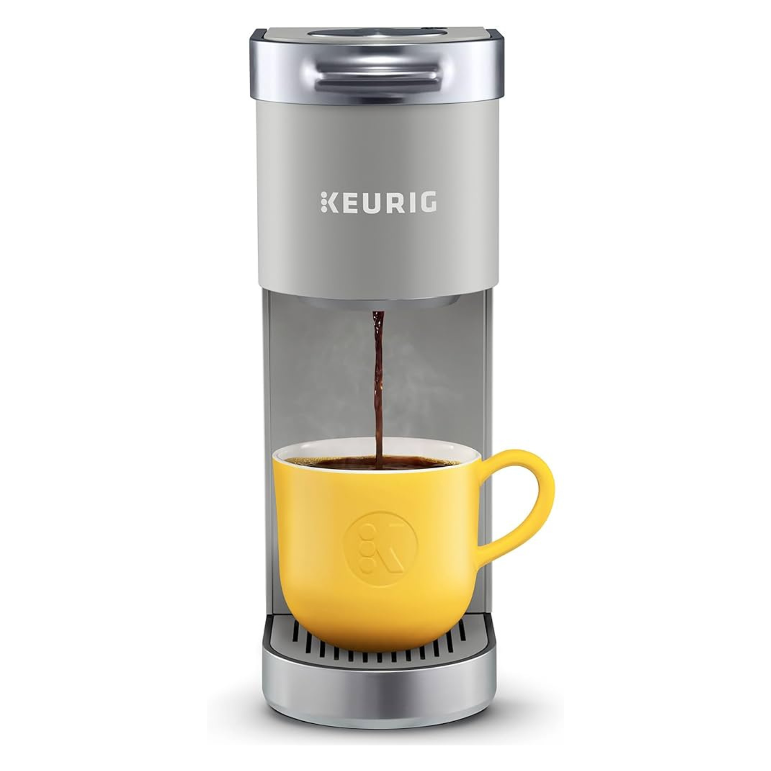 Single-serve Keurig K-Mini Plus coffee maker, grey with metallic accents, and a yellow mug underneath receiving brewed coffee. Compact and sleek design, ideal for limited space.