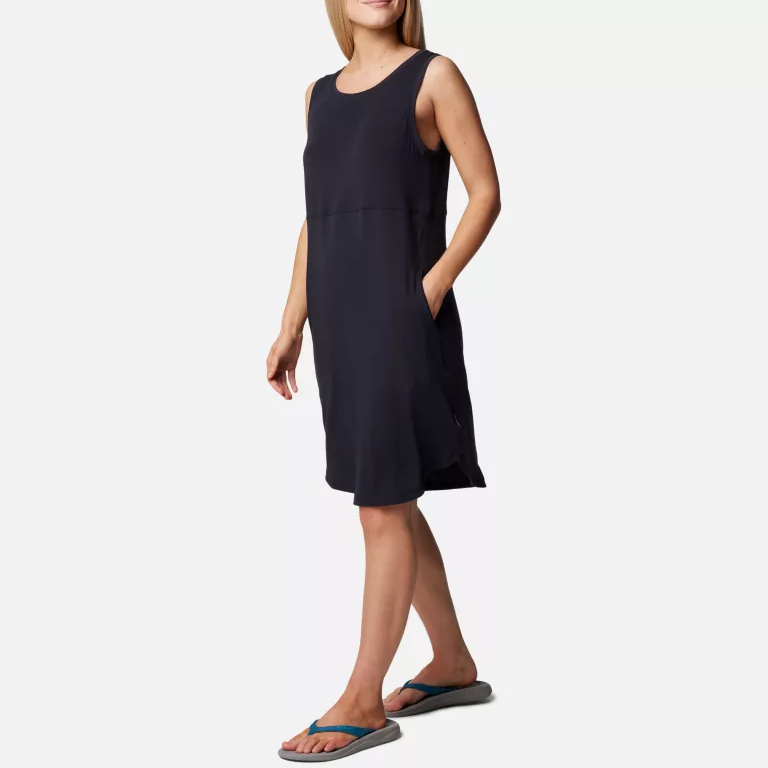 A woman is wearing a sleeveless navy blue dress with a scoop neckline and flip-flops with blue straps.