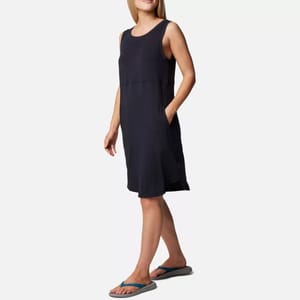 A woman is wearing a sleeveless navy blue dress with a scoop neckline and flip-flops with blue straps.