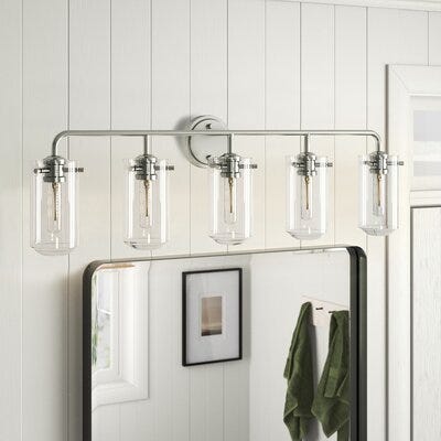 A four-bulb vanity light fixture with clear glass shades and a chrome finish, mounted above a bathroom mirror.