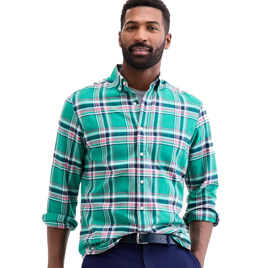 A man wearing a green plaid button-up shirt with a collar, paired with dark pants and a black belt.