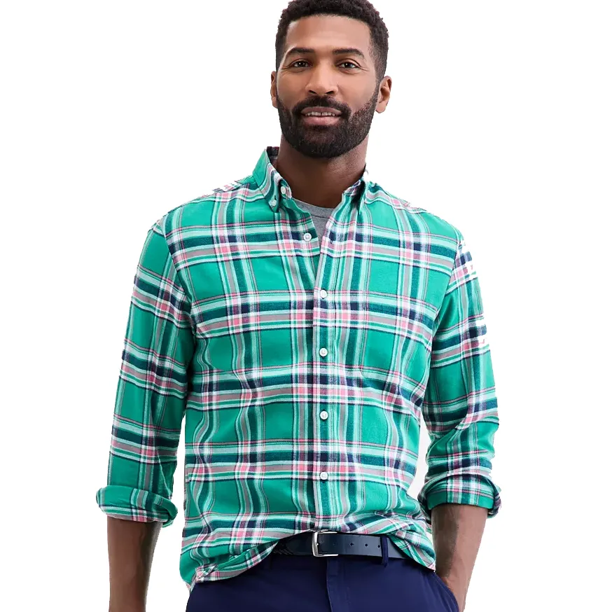 A man wearing a green plaid button-up shirt with a collar, paired with dark pants and a black belt.