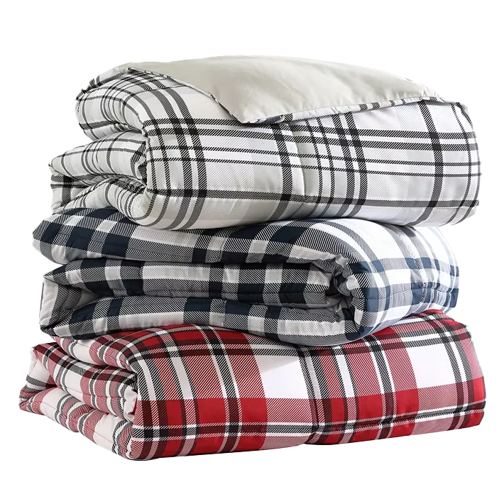 A stack of reversible down-alternative comforters with plaid patterns in shades of red, black, and white. Each comforter displays a different color combination.