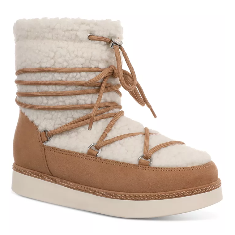 Sherpa Brooklyn Winter Boots feature a cozy, cream-colored sherpa upper with tan suede accents and wrap-around laces. They have a thick, flat outsole for stability and warmth.