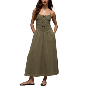 Sleeveless olive green dress with a smocked bodice, shoulder straps, bow details, and a flowing skirt. Paired with casual sandals.