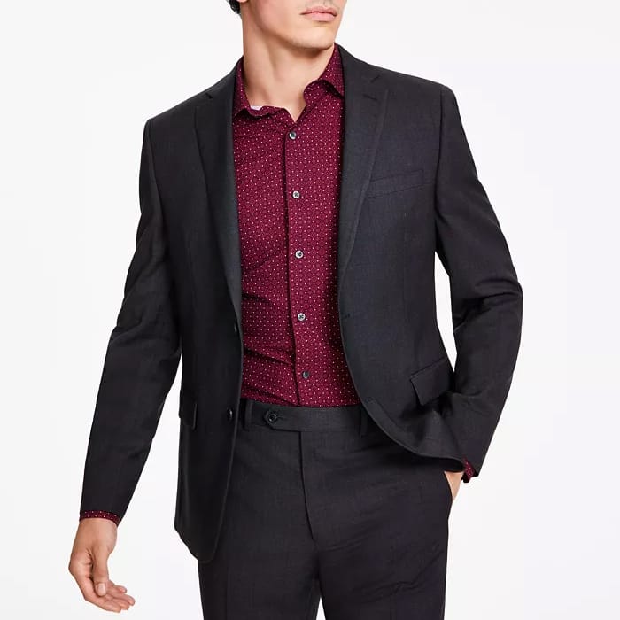 A slim-fit black check suit jacket with notched lapels, worn over a burgundy button-up shirt.