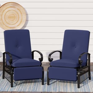Two blue cushioned patio chairs with black metal frames and curved armrests, positioned on a striped outdoor rug against a white shiplap wall.