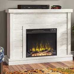White wooden electric fireplace with a realistic flame effect, topped with electronic equipment, on a hardwood floor with a patterned rug nearby.