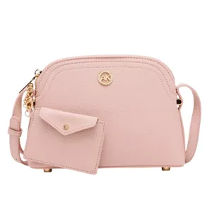 A blush pink crossbody bag with a textured finish, gold-tone hardware, and a small matching cardholder attached.