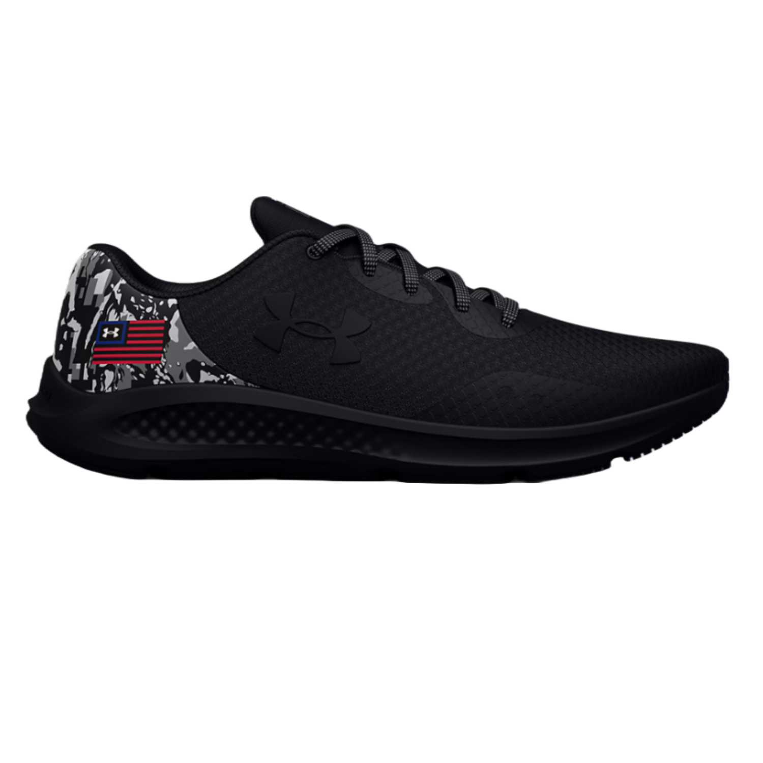 Black Under Armour running shoe with a subtle textured design, featuring a black logo, gray camo accents on the heel, and an American flag-inspired emblem.