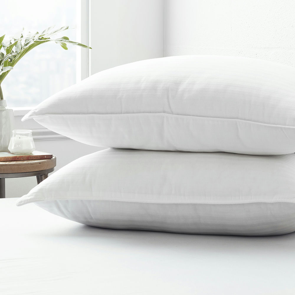 Two white pillows stacked on top of each other on a bed.