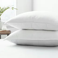 Two white pillows stacked on top of each other on a bed.