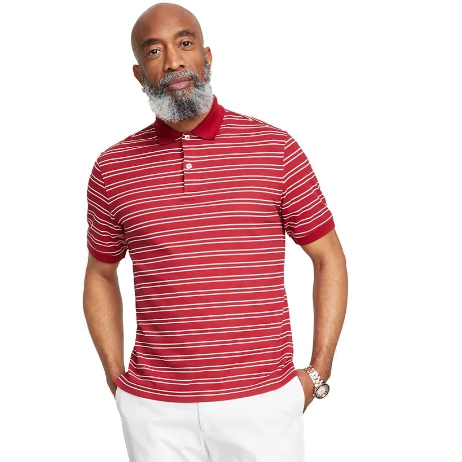 A man wears a red polo shirt with white horizontal stripes, featuring a collar and short sleeves, paired with white pants.