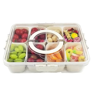 A clear, compartmentalized snack box contains red and green grapes, cherry tomatoes, assorted candies, and wrapped chocolates.