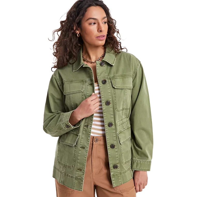 A green lightweight utility jacket with a button-down front, multiple pockets, and a relaxed fit, paired with a striped top and brown pants.