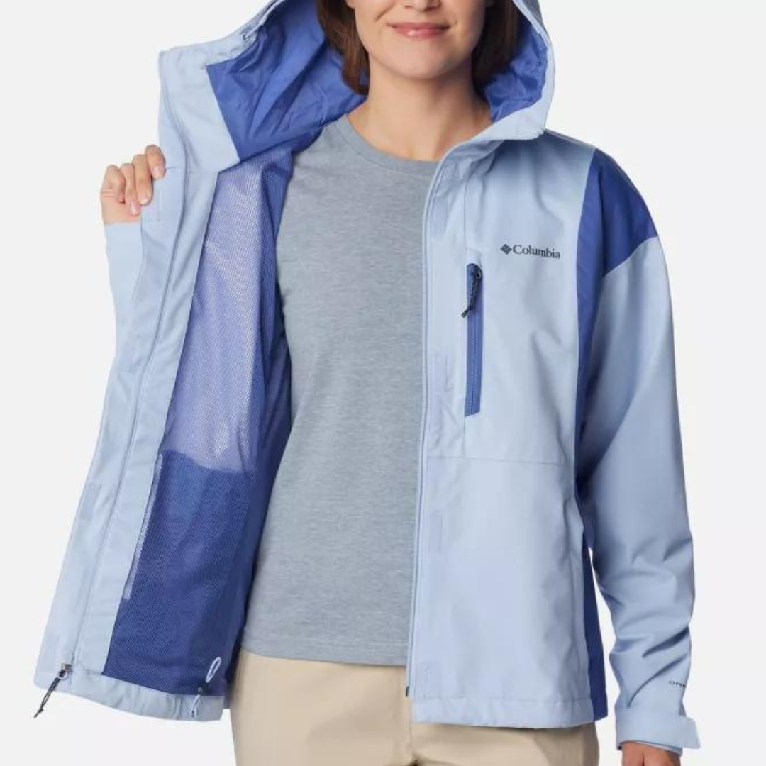 A woman wearing a light blue Columbia branded jacket with a hood and a grey T-shirt.