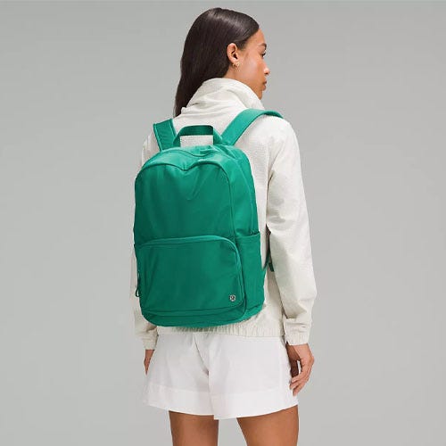 a woman with dark hair sporting a green lululemon backpack