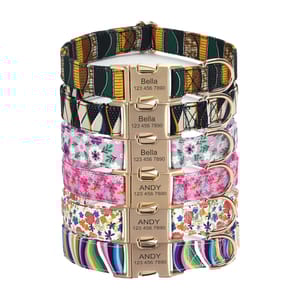 A stack of colorful pet collars with various patterns, featuring nameplates engraved with \“Bella\“ or \“Andy\“ and a phone number.