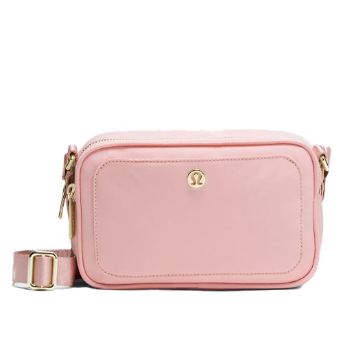 A pink crossbody bag with gold hardware, featuring a front pocket and adjustable strap, adorned with a small logo emblem.