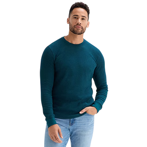 A man is wearing a teal long-sleeve sweater paired with light blue jeans.