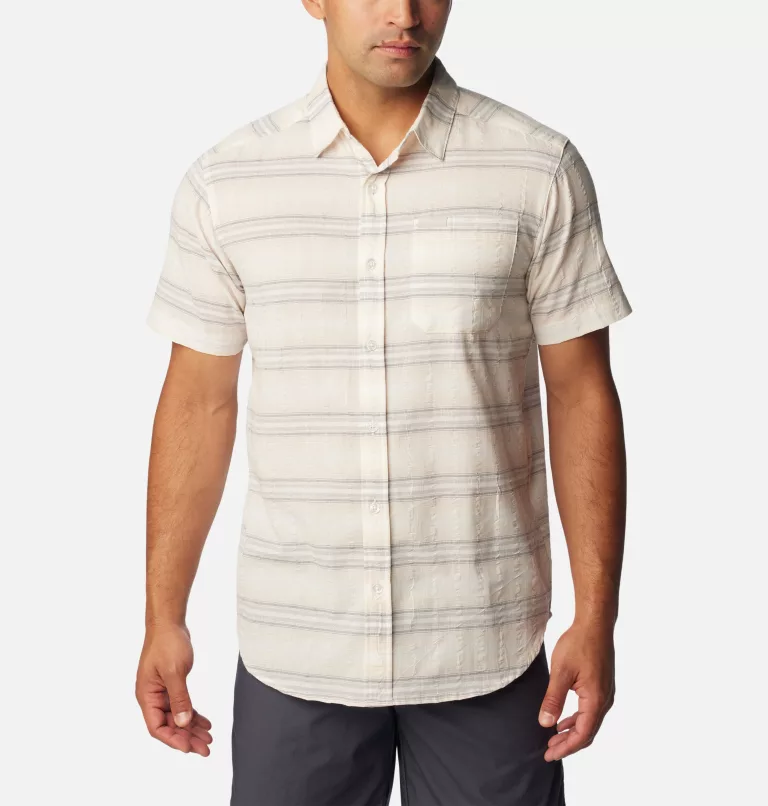 A man wearing a short-sleeved, button-up shirt with horizontal stripes.