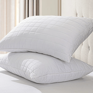 Two memory foam pillows with a quilted, grid-patterned white cover, stacked on a bed.