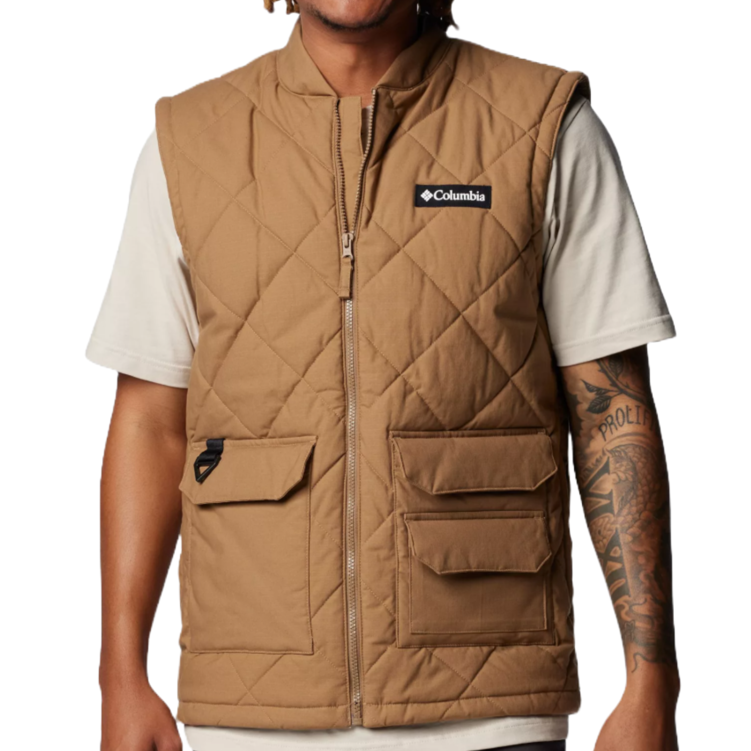 The Columbia Rad Padded Vest is a tan quilted zip-up vest with a high collar and dual front pockets. It features a visible Columbia logo on the chest and is worn over a short sleeve white shirt.