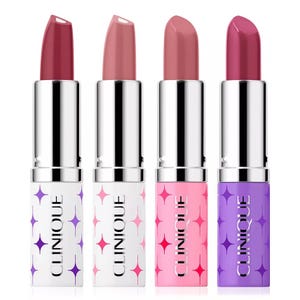 Four Clinique lipsticks in various shades, each with a distinct tube color and pattern: white with purple and pink stars, pink with red stars, and solid purple.