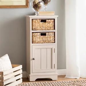 A beige cabinet with two woven baskets and a lower door sits next to a wooden crate and a neutral-toned rug, with framed artwork and decorative glass items on top.