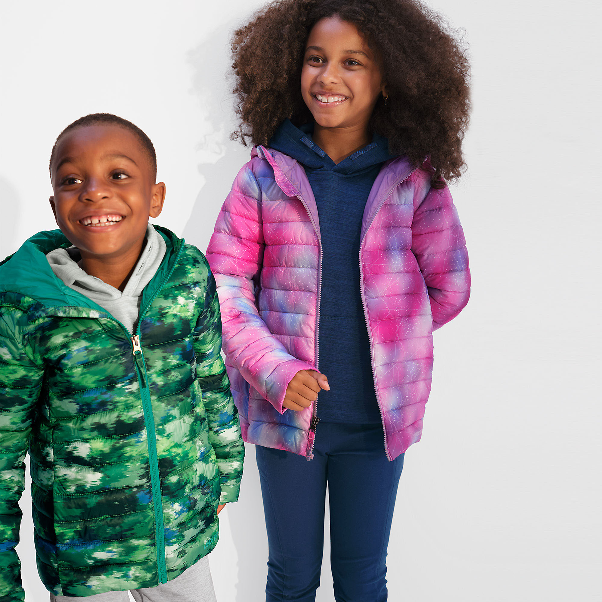 Two children are wearing Lands' End insulated jackets; one jacket has a pink and purple gradient, and the other features a green camouflage pattern.