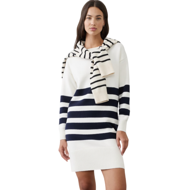 A woman wears a white and navy striped sweater dress with a matching scarf draped over her shoulders, paired with black loafers.