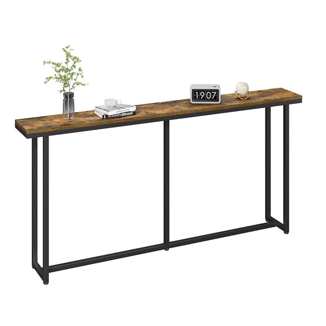 A narrow console table with a rustic wooden top and black metal frame, featuring a clock, books, a vase with green foliage, and a cup.