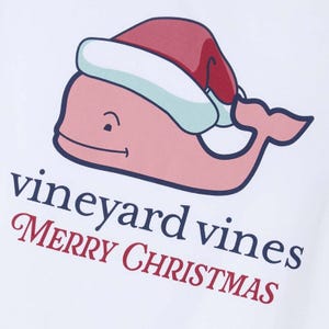 Vineyard Vines Kids' Santa Whale Tee features a smiling pink whale wearing a Santa hat, with \“vineyard vines\“ and \“Merry Christmas\“ written below in festive colors.
