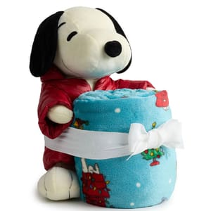 A plush Snoopy toy wearing a red jacket holds a rolled-up blue blanket featuring festive Snoopy and Christmas scenes.