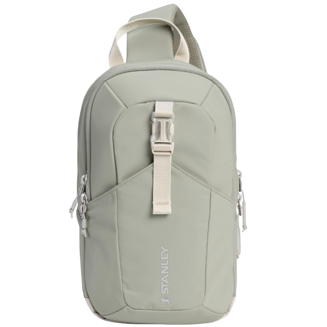 Sage green crossbody sling bag with a central buckle strap and dual zippers, featuring \“Stanley\“ branding on the front.