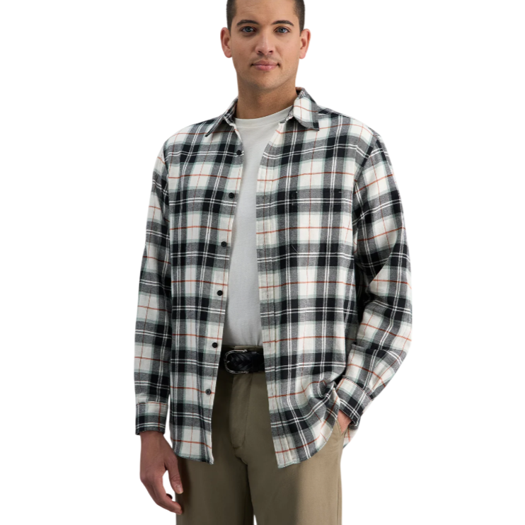 A man is wearing a plaid button-up shirt in black, white, and orange over a white T-shirt, paired with khaki pants and a black belt.