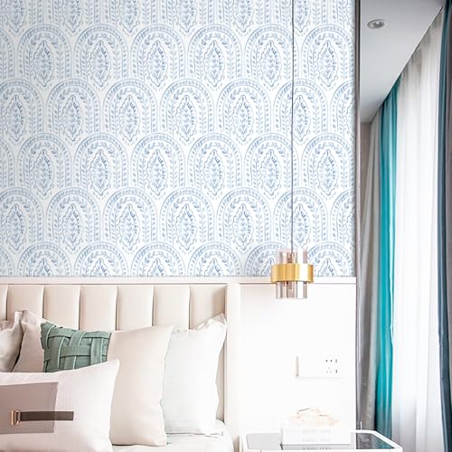 A styled interior featuring a patterned blue and white wallpaper, cream upholstered headboard, decorative pillows, a glass side table, and a modern pendant light.