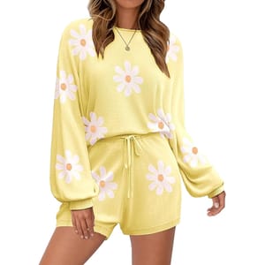 Yellow knit lounge set with long sleeves and shorts, featuring white daisy patterns with pink centers. The top has a relaxed fit, and the shorts have an elastic waistband with a drawstring.