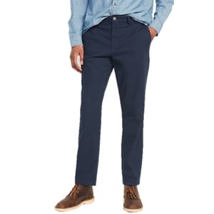 A person wears navy blue chinos, light blue button-up shirt, and brown leather boots.